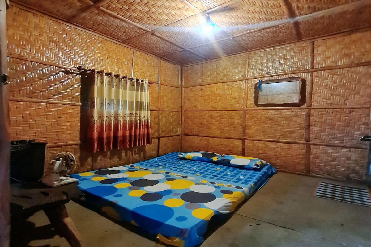 Una habitación con una cama, un ventilador y una ventana pequeña.