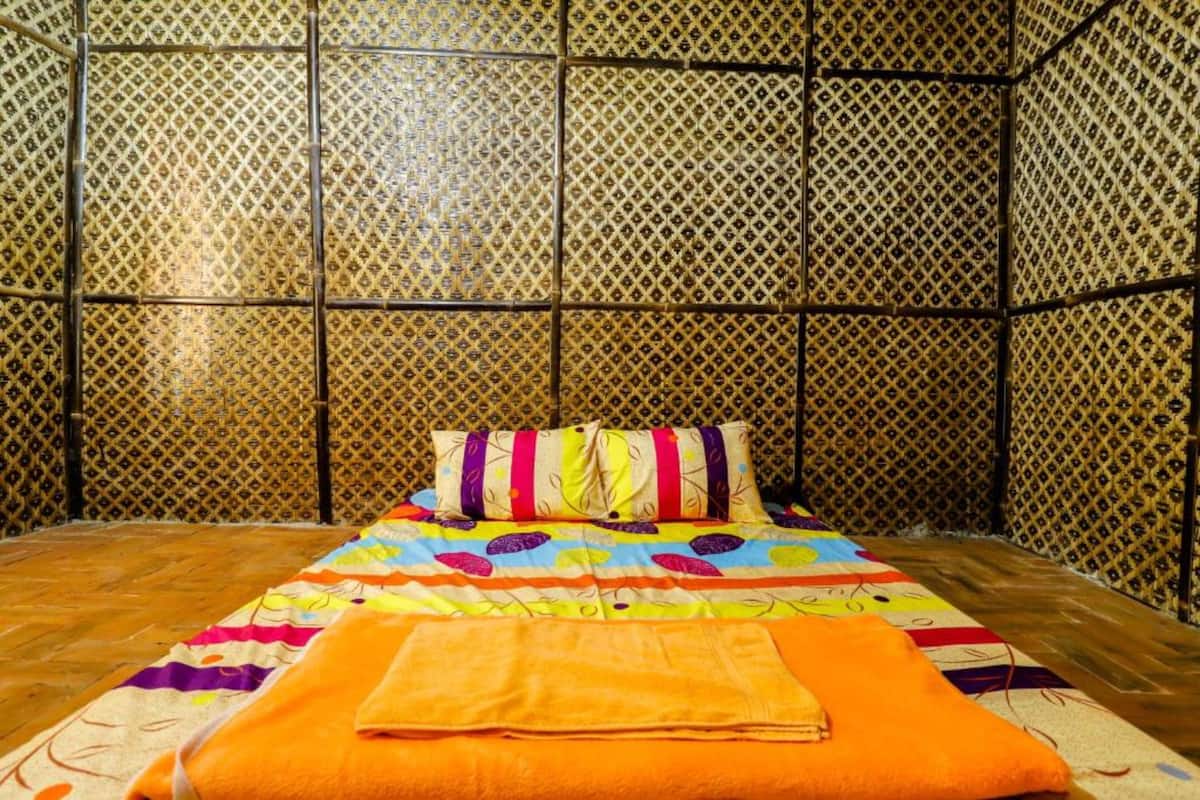 Una habitación con una cama, un edredón colorido y una pared estampada.