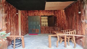 A rustic wooden exterior with a stone-paved entrance, a wooden table and chairs, and a woven basket. - Larasati Homestay (Kalirejo)