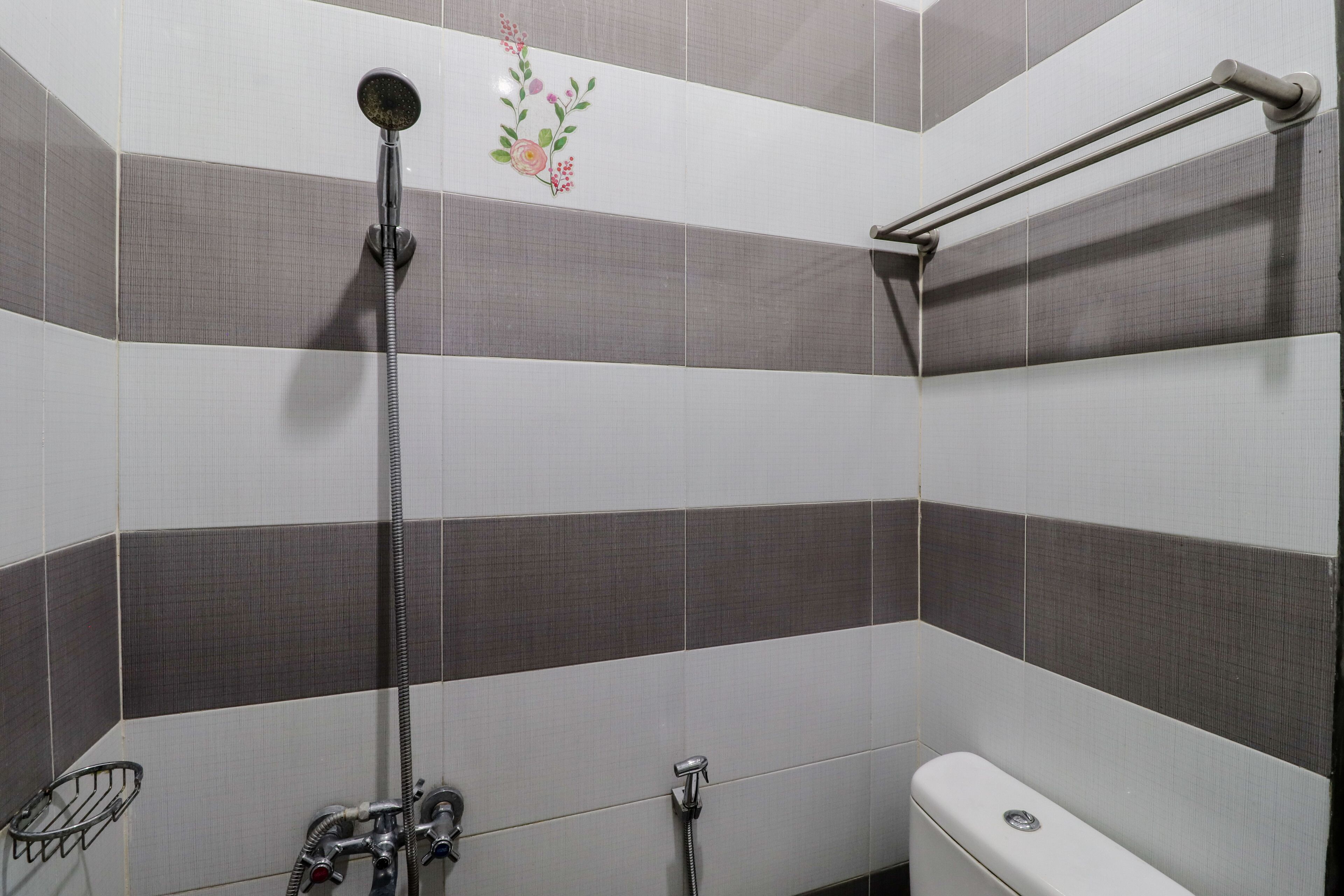 Une salle de bain équipée d’une douche, de toilettes et d’une barre d’appui.