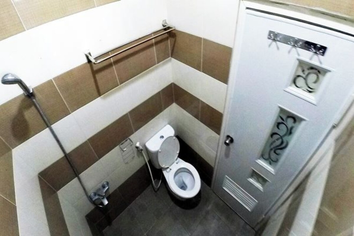 Une petite salle de bain équipée de toilettes, d’un sèche-mains et d’une armoire métallique avec un distributeur d’eau.