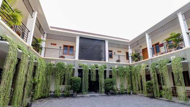 A courtyard with a central open space, surrounded by buildings with balconies and potted plants. - Khatarina Female Residence - Female Only - khusus wanita (Depok)