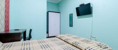 Un dormitorio con cama, escritorio, silla, armario y televisor montado en la pared.