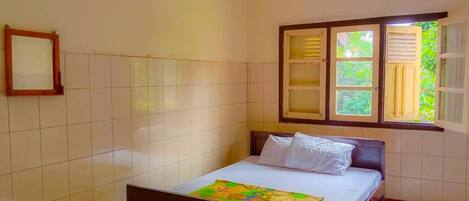 A bedroom with a bed, a window with shutters, and a tiled wall.