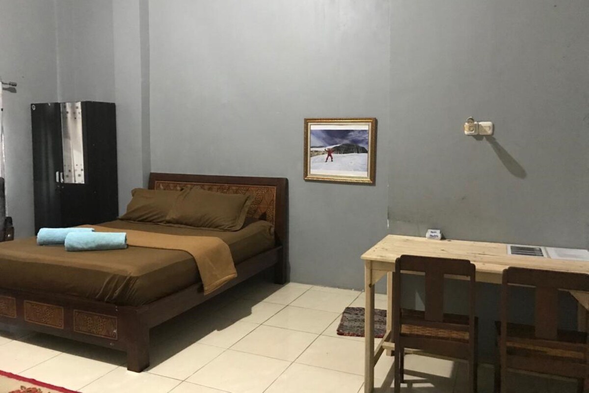 A bedroom with a bed, a desk, and a chair.