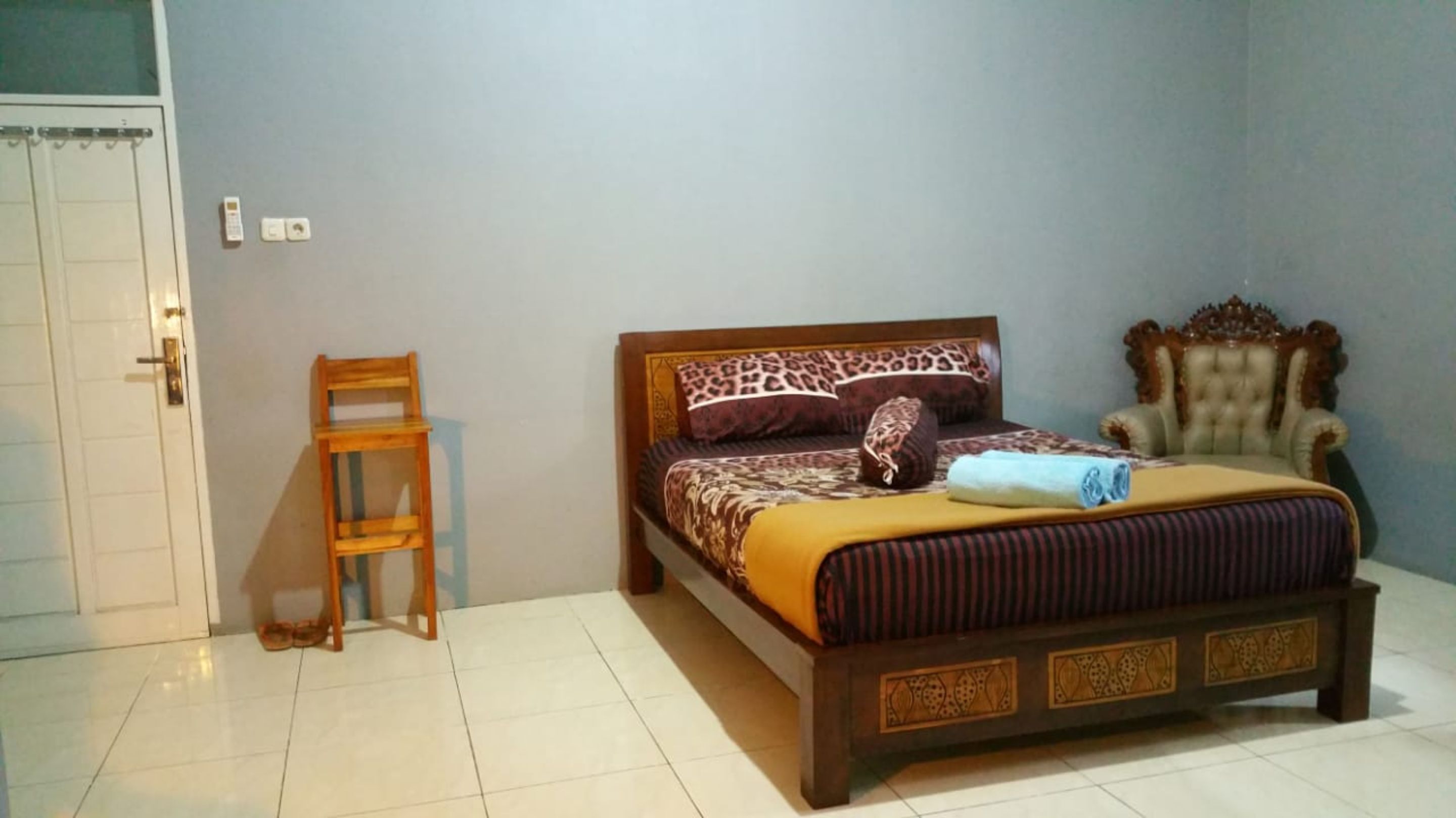 A bedroom with a bed, a chair, and a wardrobe.