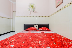 A bedroom with a bed, a wall-mounted fan, and a decorative border. - Losmen Panorama (Parangtritis)