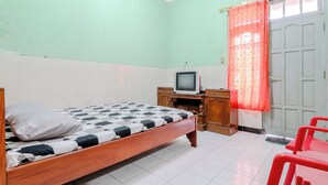 Un dormitorio con cama, televisor, armario y una puerta con cortina.