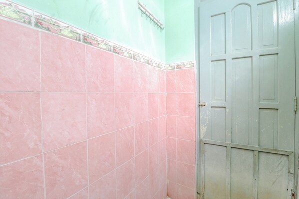 Un baño con azulejos rosas y una puerta blanca.