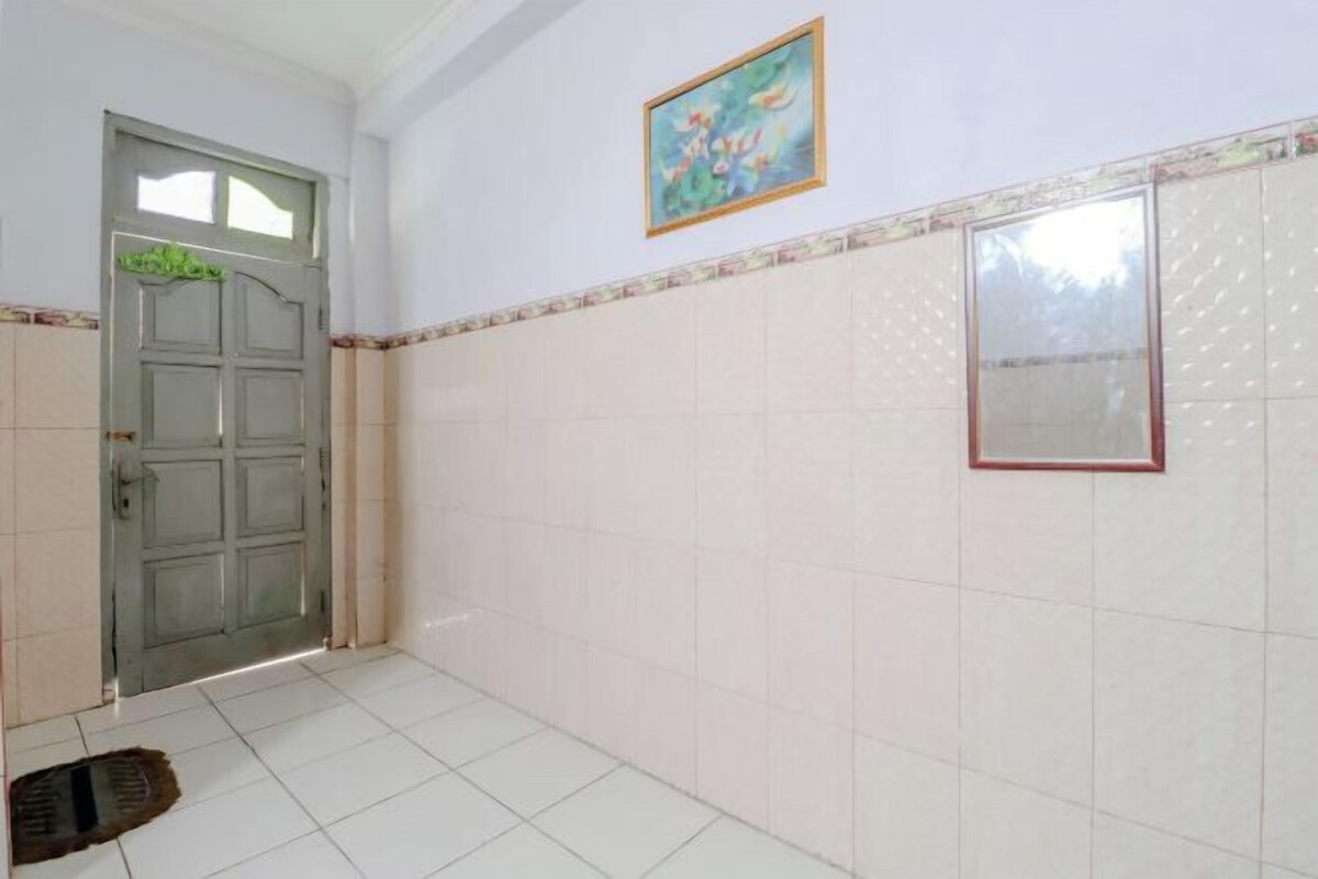 Un pasillo con suelo de baldosas, una puerta con ventanal y un cuadro en la pared.