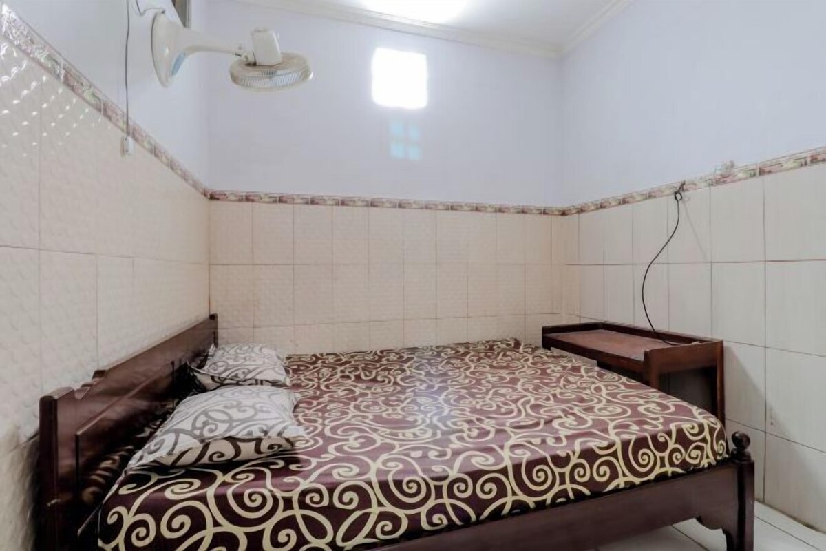 Un dormitorio con cama, mesita de noche y ventilador de techo.