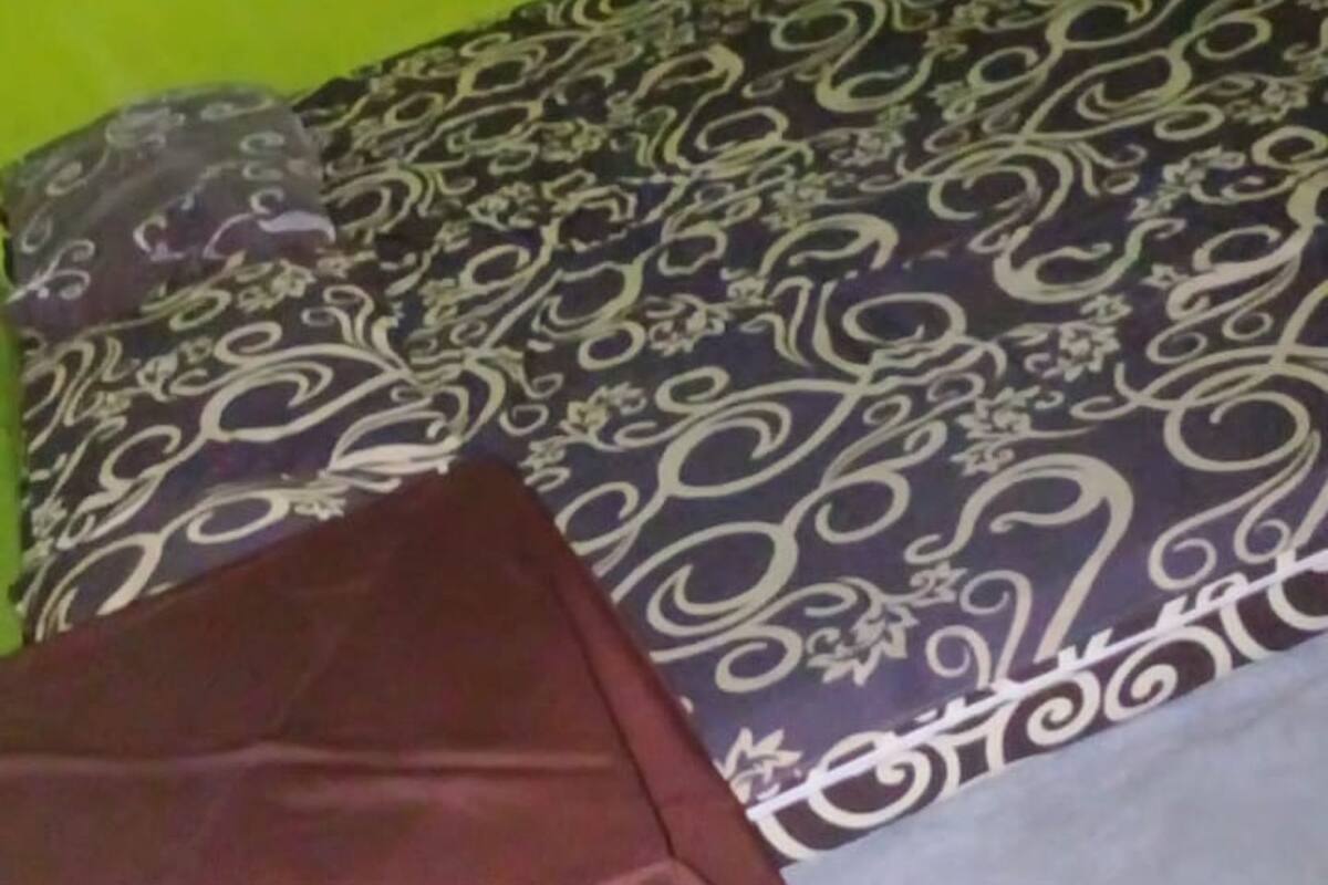 A bed with a patterned bedspread and a dark-colored blanket.