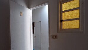 Une pièce avec une porte blanche, une fenêtre ornée de vitraux aux motifs dorés et une prise électrique visible.