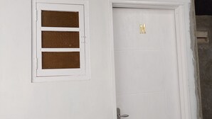 Une porte blanche avec une petite fenêtre et une enseigne dorée en forme de « M ».