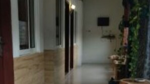Un couloir avec un banc en bois, une plante en pot et un climatiseur fixé au mur.