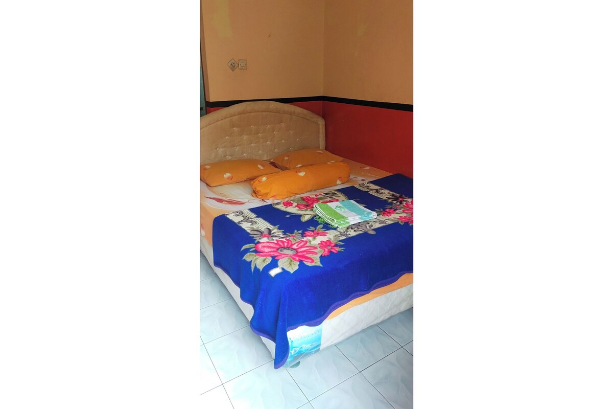 A bed with a floral bedspread, orange pillows, and a headboard.