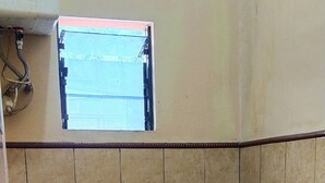Un bagno piccolo con il water, un secchio verde e una finestra sopra il water.