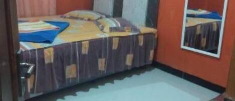 A small, compact room with a single bed, a mirror, and a small table.