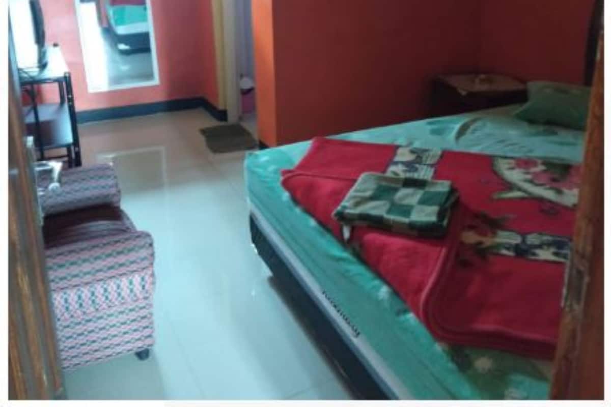 A bedroom with a bed, a chair, a small table, and a mirror.