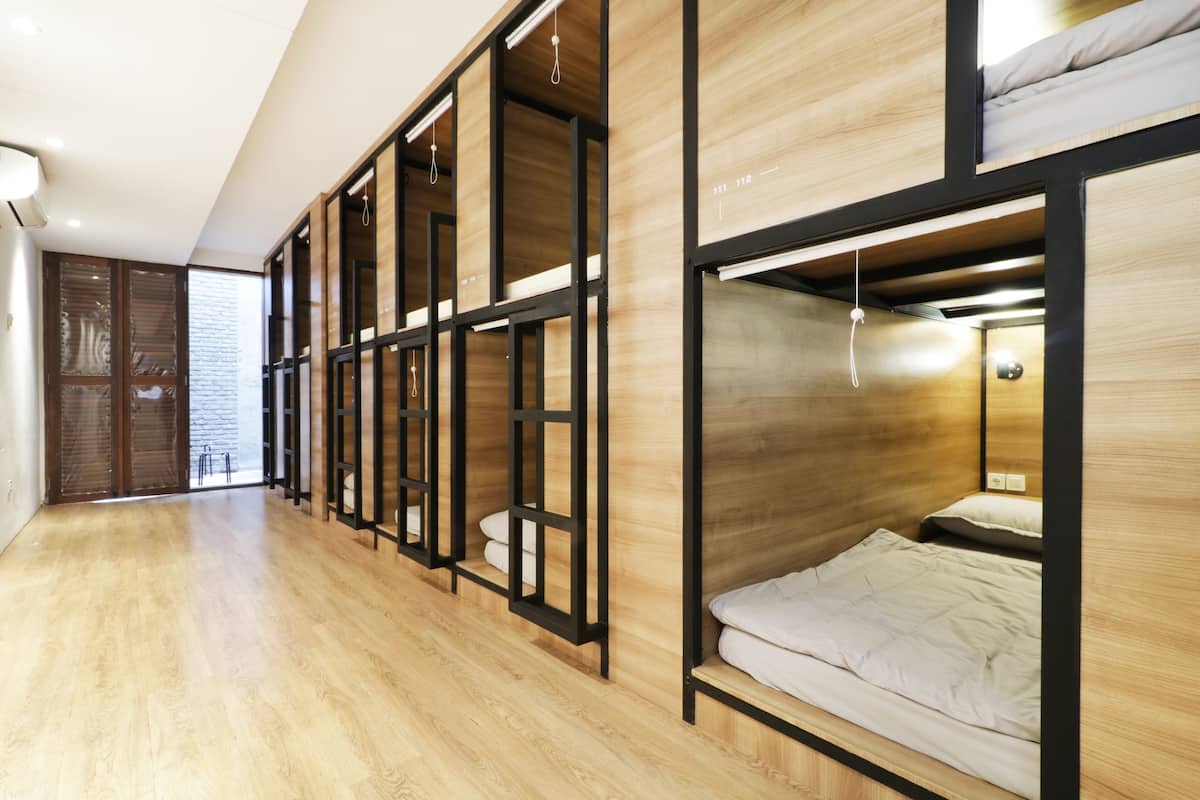 A modern hotel room with wooden floors, built-in wardrobes, and a bunk bed.