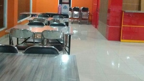 A dining area with tables and chairs, a vending machine, and a red counter. - 7 Dream Hotel (Palembang)