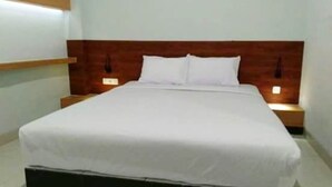 A neatly made bed with white linens in a hotel room. - 7 Dream Hotel (Palembang)