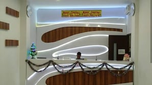 A reception desk with a Christmas-themed sign, a small Christmas tree, and garlands. - 7 Dream Hotel (Palembang)
