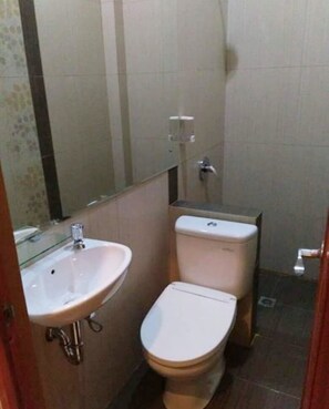 A small bathroom with a white sink, a toilet, and a mirror. - 7 Dream Hotel (Palembang)