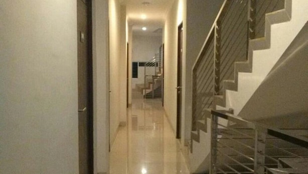A hallway with a shiny tiled floor, a staircase with metal railings, and a door on the left. - 7 Dream Hotel (Palembang)