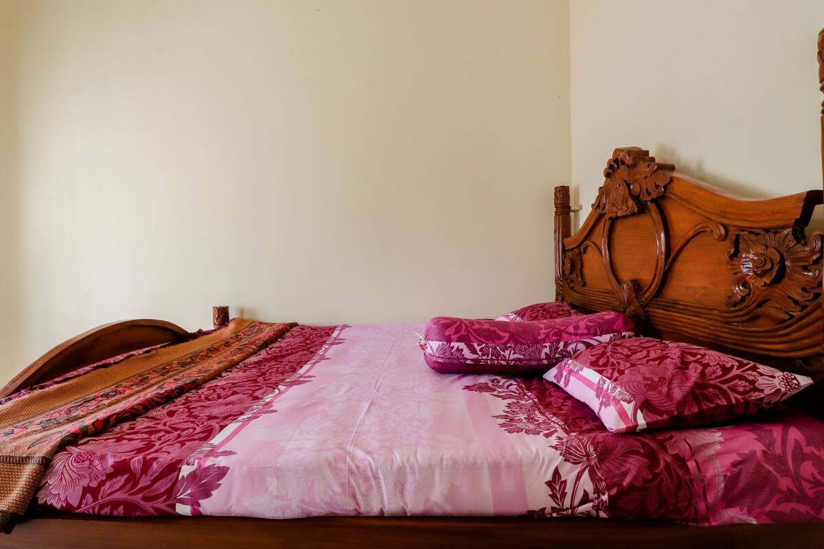 A bed with a wooden headboard, a patterned bedspread, and multiple pillows.