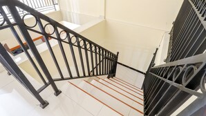 Eine Treppe mit schwarzen Metallgeländern und weiß gefliestem Boden.
