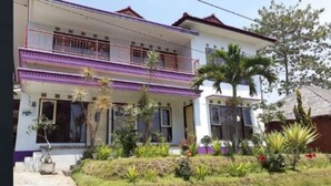 A two-story house with a balcony on the upper floor, surrounded by a well-maintained garden with various plants and a small pond. - Villa Panderman View (Batu)