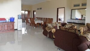 A spacious living area with a dining table, sofas, and a kitchen area with cabinets and a refrigerator. - Villa Panderman View (Batu)