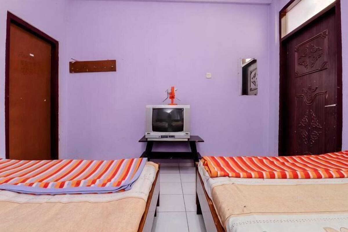 A room with two beds, a television, and a door.
