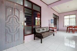 A room with a sofa, a table, and chairs. - Penginapan Sedyo Rahayu (Pakem)