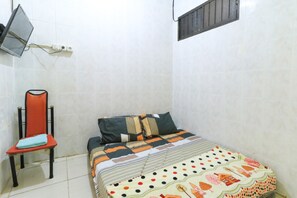 A small, clean room with a bed, a chair, and a TV mounted on the wall.