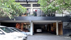 A parking area with several cars and a motorcycle, a building entrance, and a signboard.