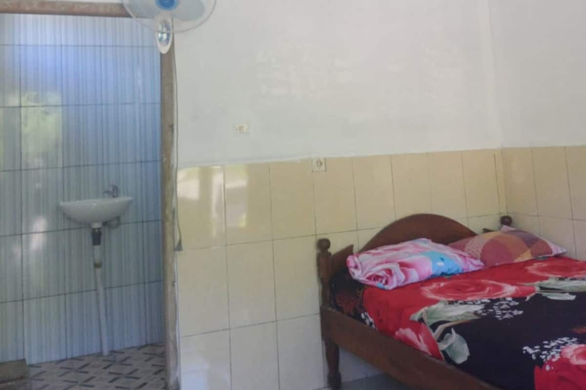 A bedroom with a bed, a ceiling fan, a window with curtains, and a sink in the corner.