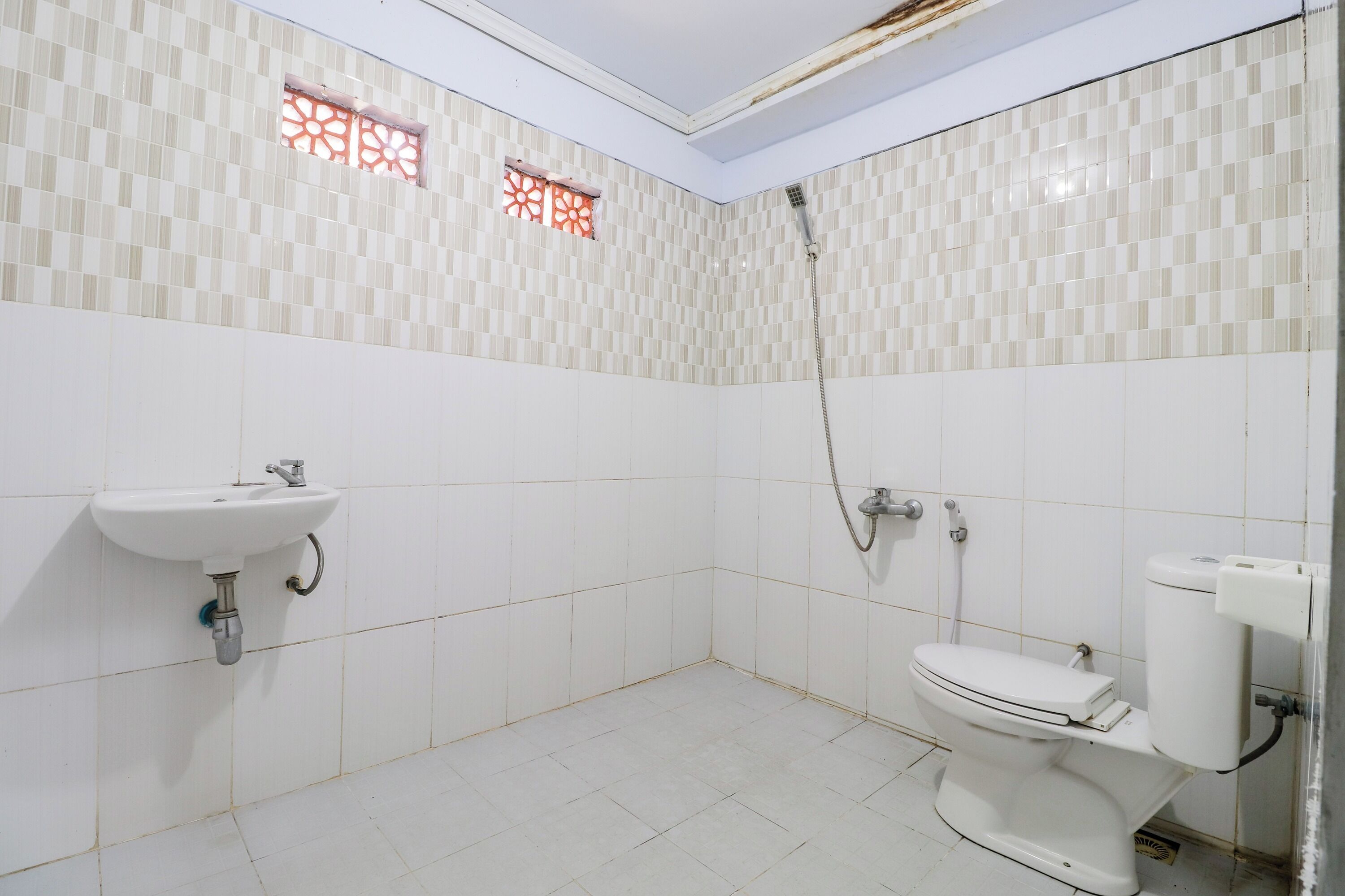 A bathroom with white tiled walls, a sink, a toilet, and a shower.