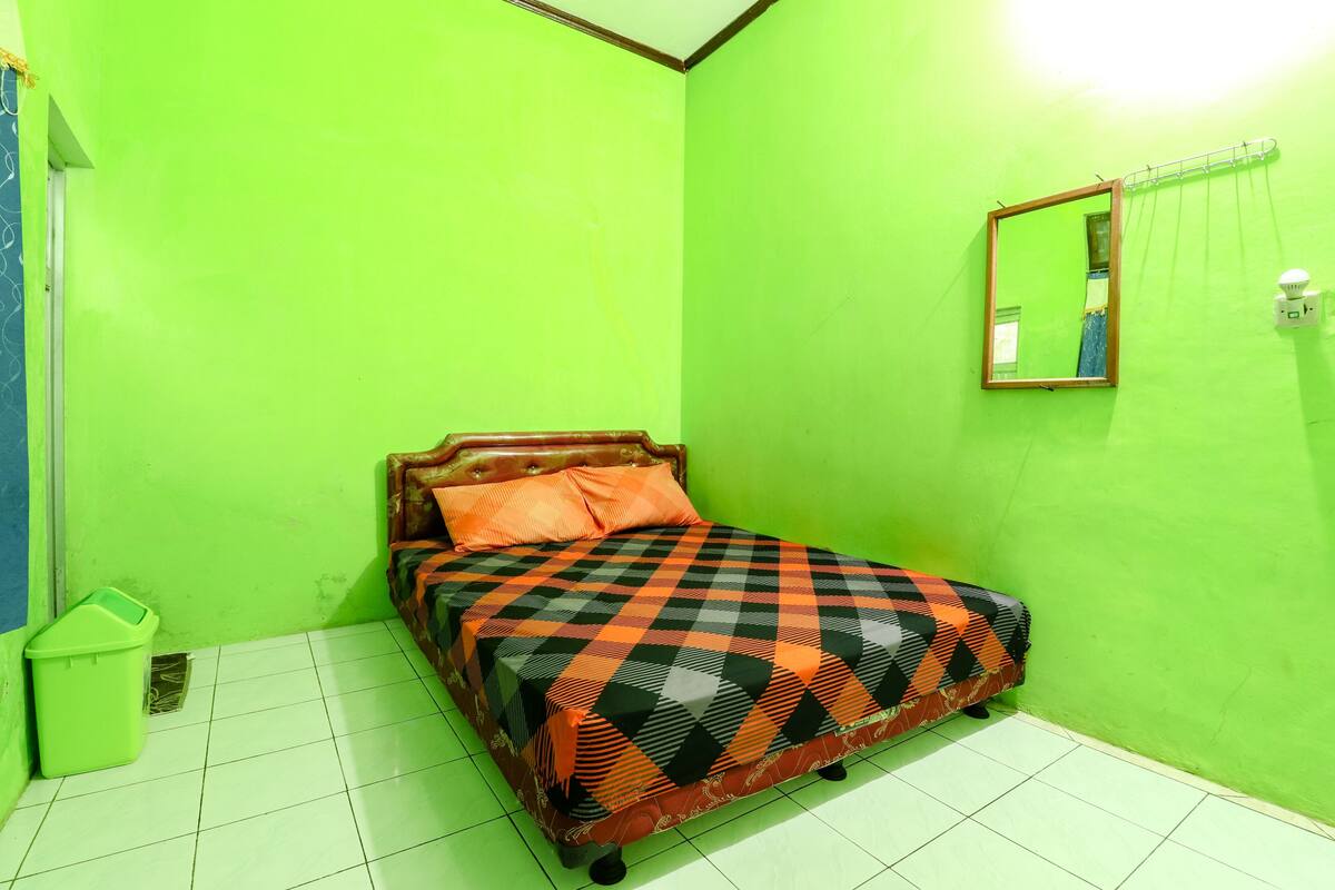 A room with a bed, green walls, and a mirror.