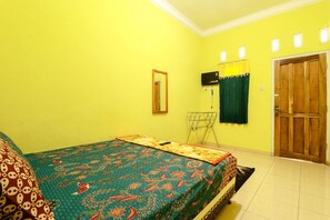 A room with a bed, a wooden door, a wall-mounted TV, and a mirror. - Willy Homestay (Borobudur)