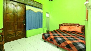 A room with a bed, a wooden door, a window with blue curtains, and a green wall. - Willy Homestay (Borobudur)