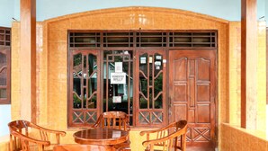 A wooden door with a sign that reads "Homestay Willy" and a tiled entrance area with a small table and chairs. - Willy Homestay (Borobudur)