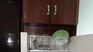 A compact kitchen with a built-in sink, a dish rack above the sink, and a cabinet with two handles. - Rumah Amanda Residence (Palangkaraya)