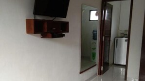 A hallway with a tiled floor, a mounted television, a mirror, and an air conditioning unit. - Rumah Amanda Residence (Palangkaraya)