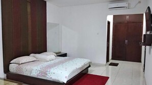 A bedroom with a bed, a red rug, a wardrobe, and an air conditioning unit. - Rumah Amanda Residence (Palangkaraya)