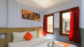 A hotel room with a bed, a painting on the wall, and a window with red curtains. - deSeruni Guest House (Dalung)