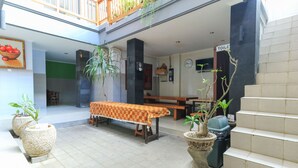 A spacious indoor area with a dining table, chairs, and potted plants. - deSeruni Guest House (Dalung)
