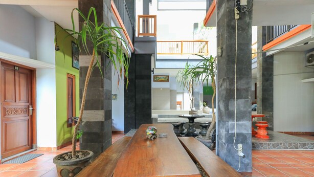 A spacious indoor area with a wooden bench, potted plants, and a tiled floor. - deSeruni Guest House (Dalung)