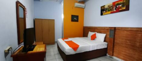 Una habitación de hotel con cama, escritorio, armario y aire acondicionado.